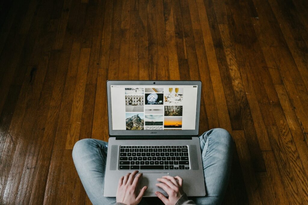 Person using a laptop while sitting on a hardwood floor