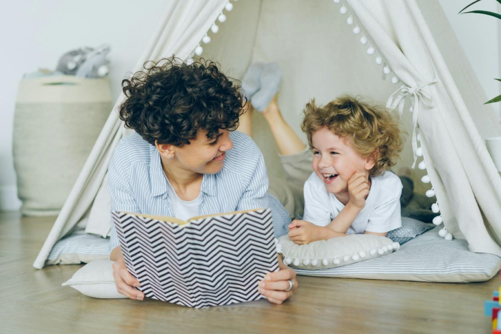 An adult reading a story to a toddler while lying on the floor